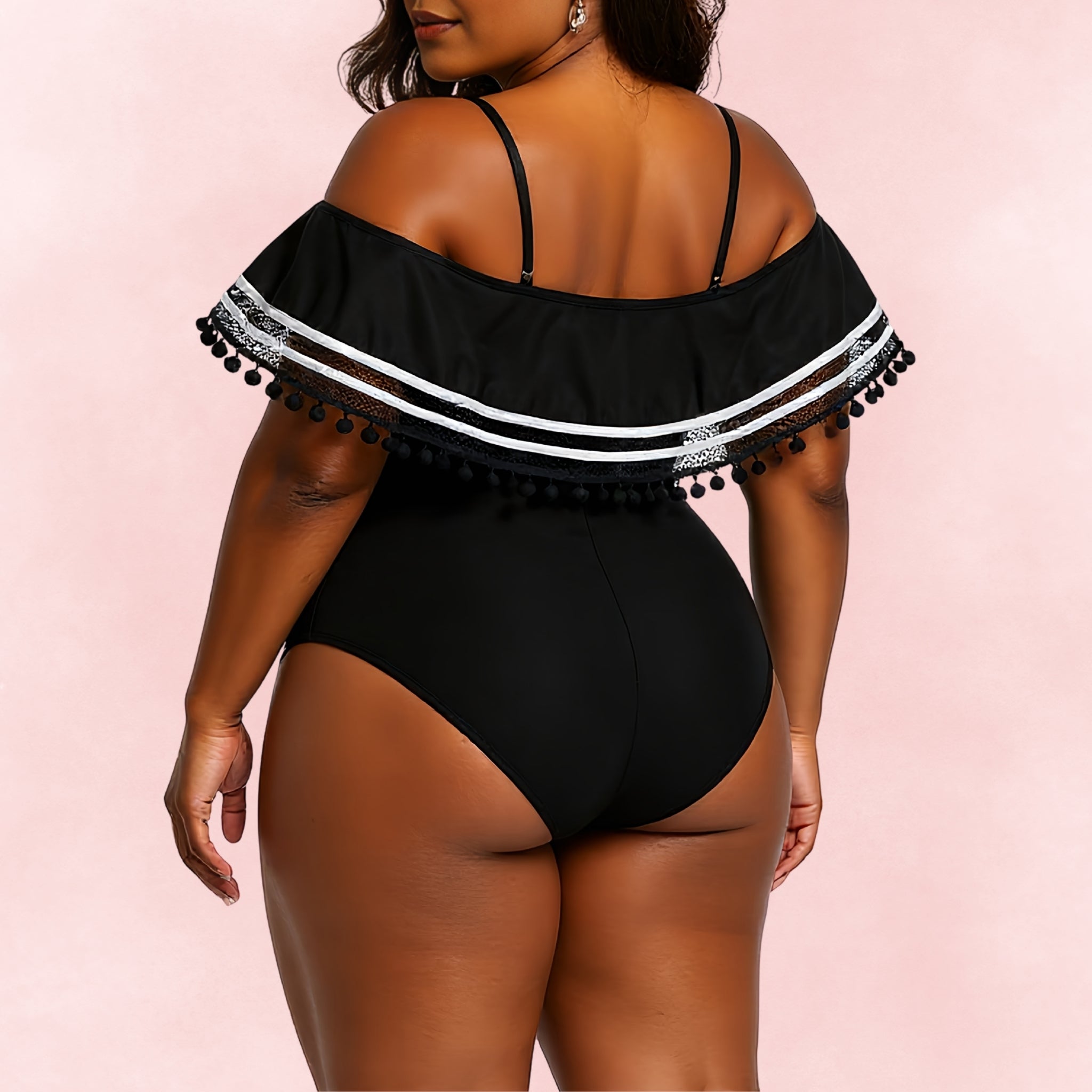 Back view of plus size black one piece swimsuit with off-shoulder ruffle, lace detail, and pom pom trim.