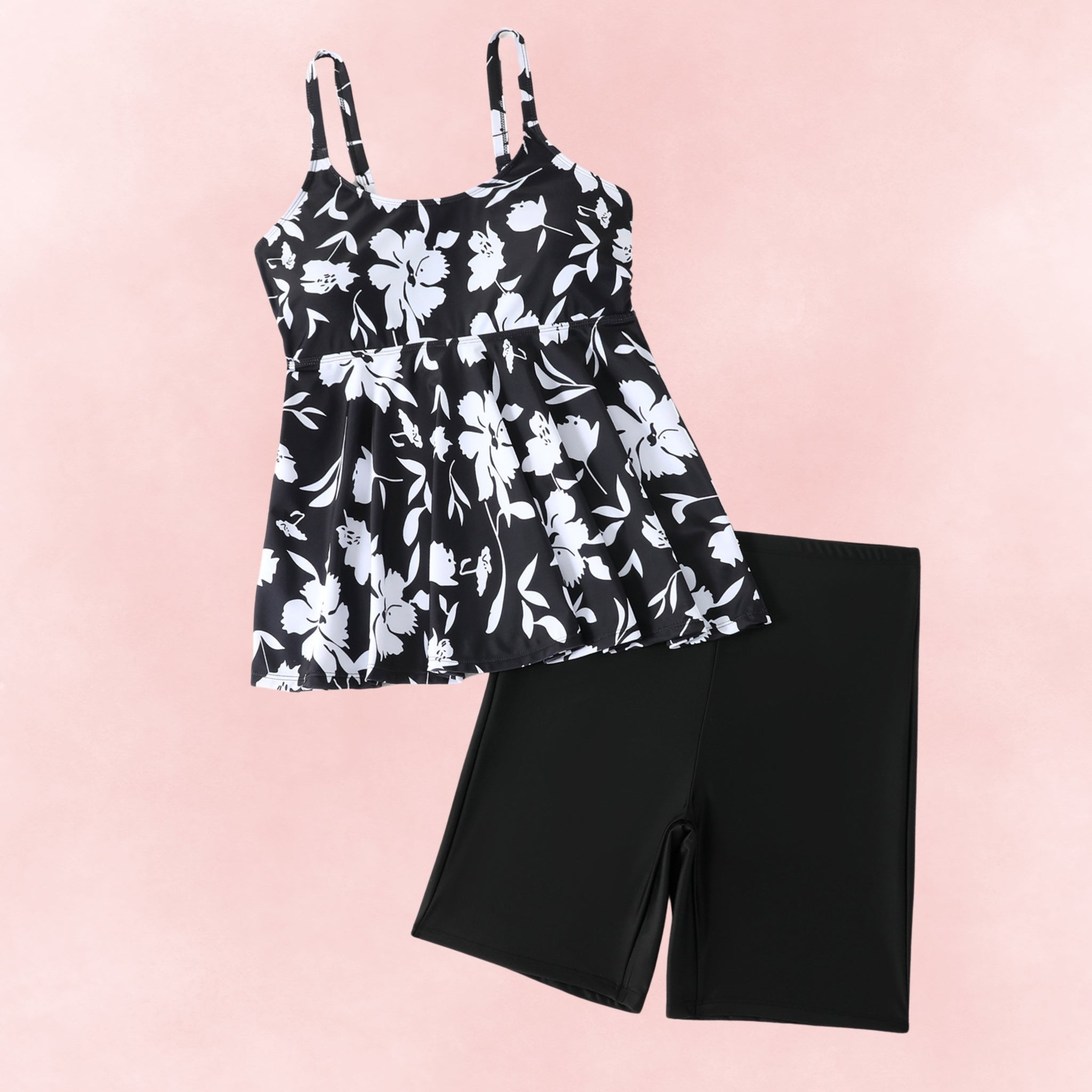 Black and white floral plus size tankini top with adjustable straps, paired with black swim shorts, flat lay display