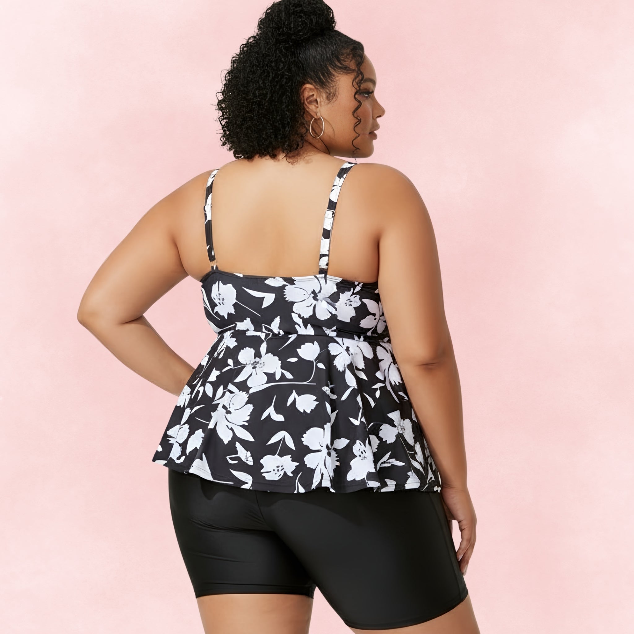 Back view of plus size model wearing black and white floral tankini top with matching swim shorts