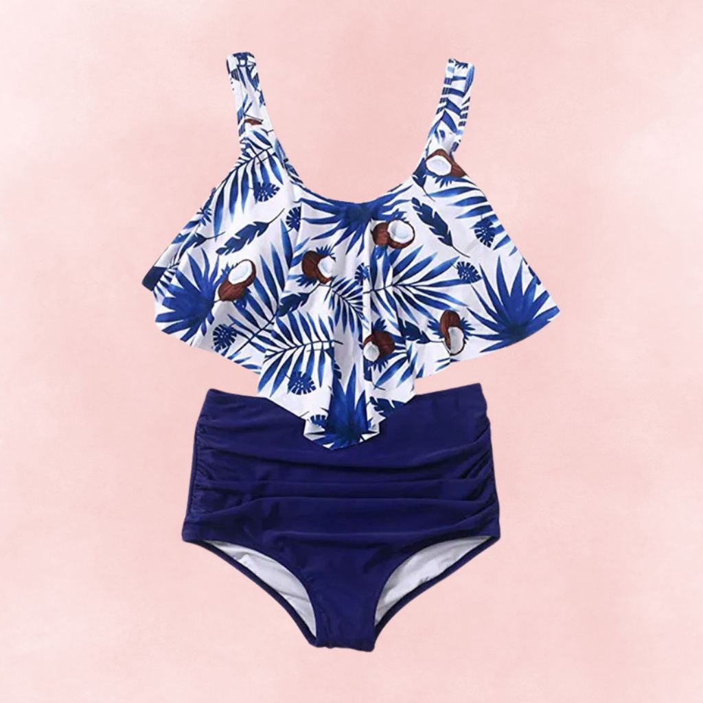 Flat lay of plus size bikini with white and blue coconut leaf print ruffle top and navy high waist bottoms