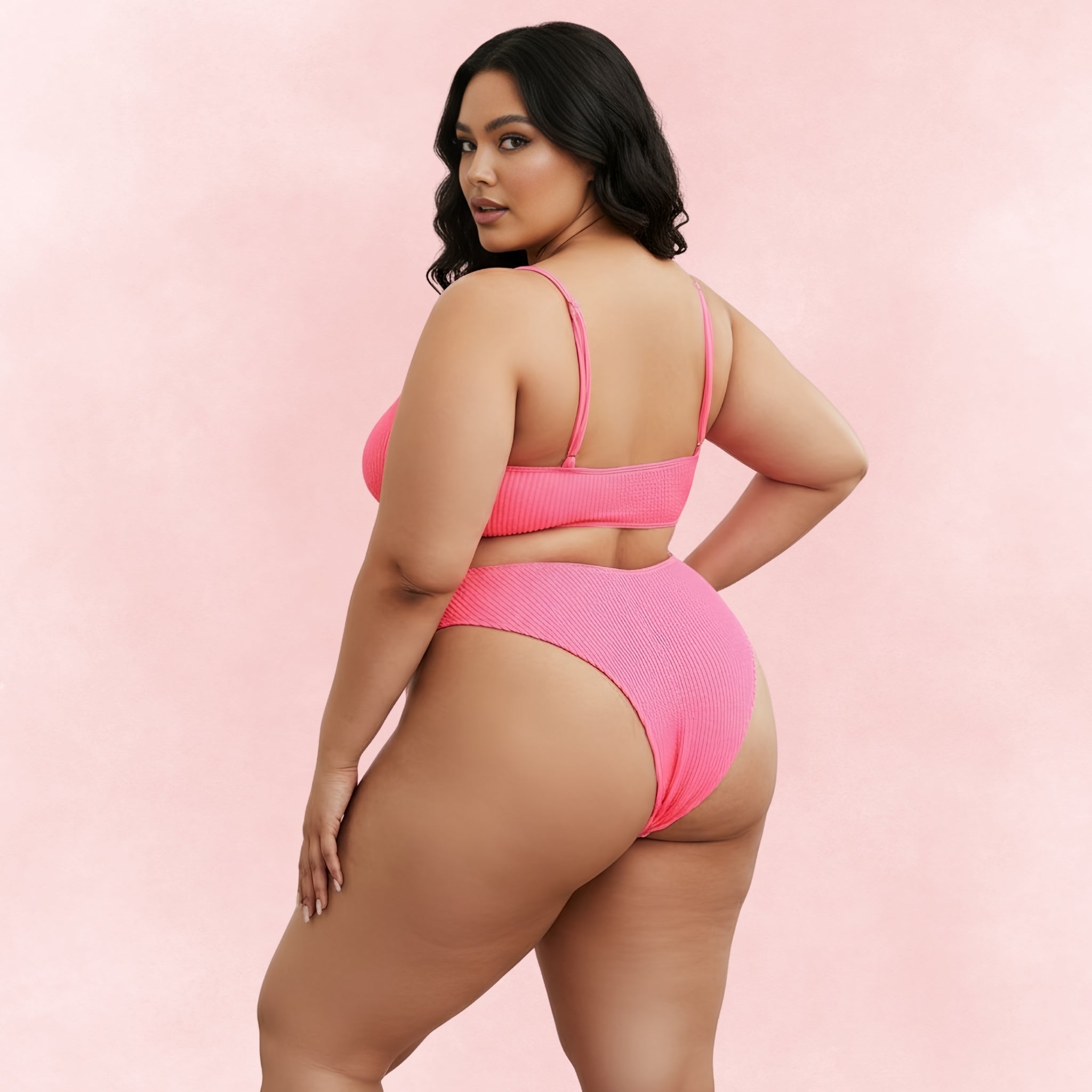 Back view of plus size woman wearing hot pink textured bikini with scoop back top and high waist bottoms