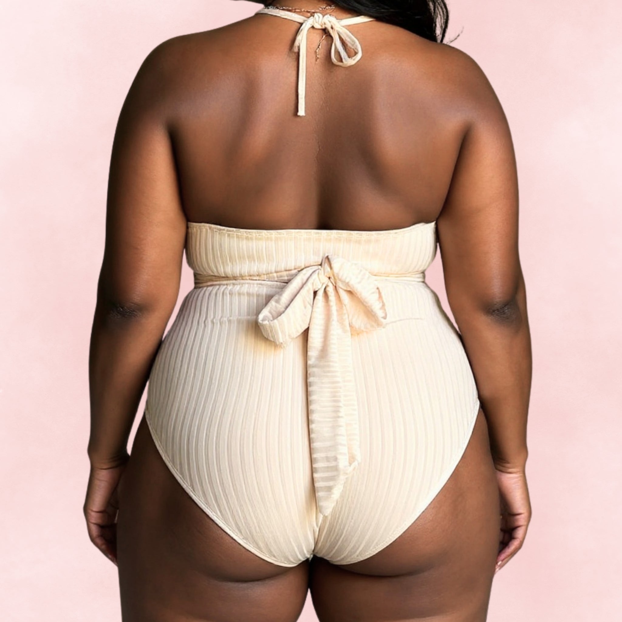 Back view of plus size beige ribbed halter swimsuit with bow tie closure and open back